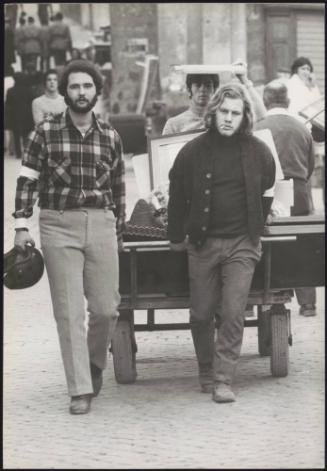 Threee young men use a cart to carry salvaged household items in the aftermath of an earthquake in Tuscany that left about 5,000 homeless