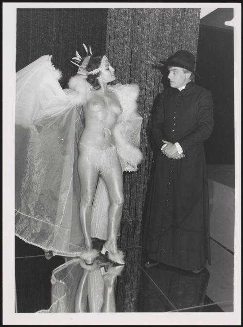 A woman bares her breasts to a clergyman
