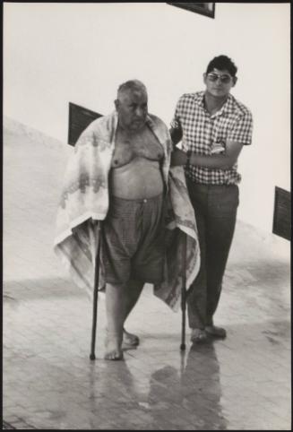 A  freshly baptised Jehovah's Witnesses on crutches is led away from the swimming pool, Genova