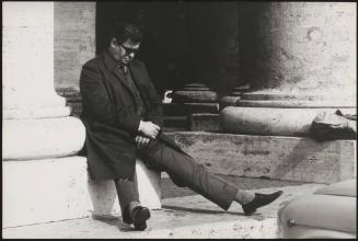 An onlooker having a rest against one of the columns of St. Peter's  colonnade, Vatican City, Rome