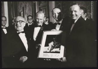 The astronauts from Apollo 11, Neil Armstrong, Michael Collins and Buzz Aldrin being presented with a framed photo of their landing on the moon 
