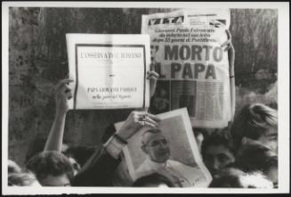 Members of the public hold up newspaper clippings headlining the death of Pope John Paul I