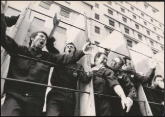 Workers from a Coca-Cola bottling factory leaning against rungs on a vehicle protesting and chanting