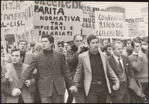 A group of men, part of the labour trade unions, link hands and lead a protest for contract reforms