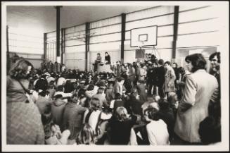 People gathering for a meeting in a crowded gymnasium at a left-wing secondary school