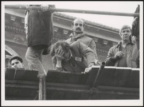 A man with his head in his hands on a wooden platform overlooked by others
