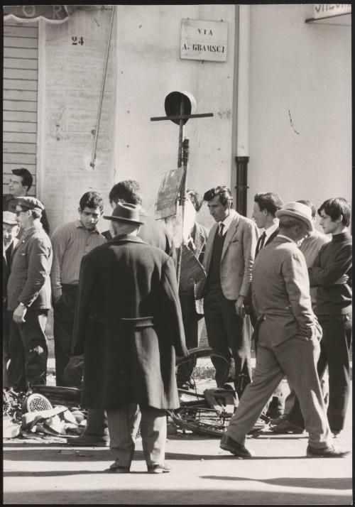 A crowd of onlookers surrounding twisted metal of a bicycle in the streets of Battipaglia, 1969