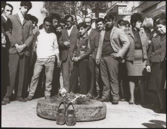 A group of people grieve at a makeshift shrine made from a tyre, flowers and a pair of shoes, in Battipaglia, 1969
