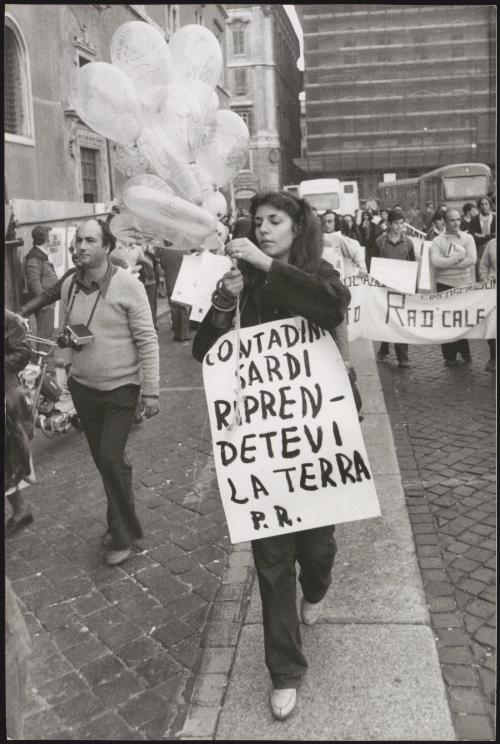 A woman carrying balloons and a poster calling for Sardinians' rights to their land, against military bases being set up there