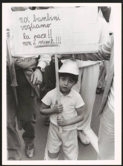A child holding a banner calling for peace against the nuclear missiles