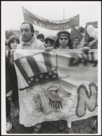 A man and woman marching with a hand painted banner at an anti-American protest 