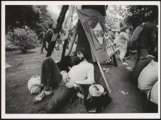 A young couple rest by a tree at a protest