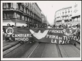 Milan 1982. A crowd of protesters march behind a large banner from the Florence quarter of the P.C.I, down a street at a communist  peace march 
