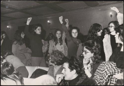 Women march through a crowded room, during a feminist protest in Rome, 1971