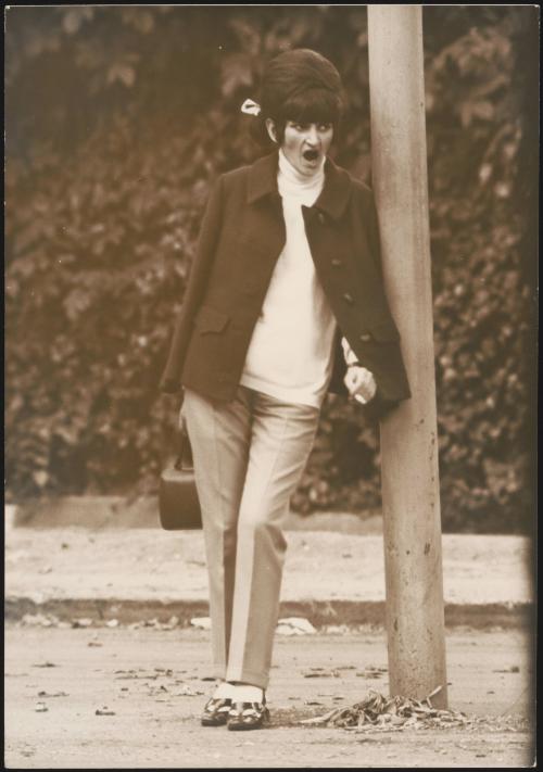 A  female prostitute leans against a  telegraph pole