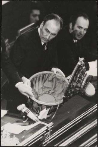 A politician opens the voting pot used in Parliament 