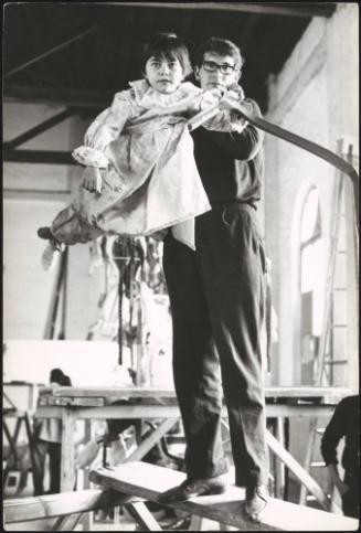 Children being prepared for a religious procession, dressed as angels and suspended on structures to appear as though they are flying
