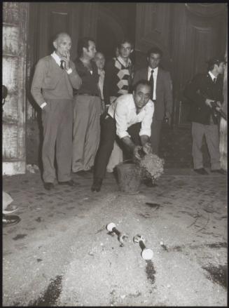 A man throws sand from a bucket on to the street