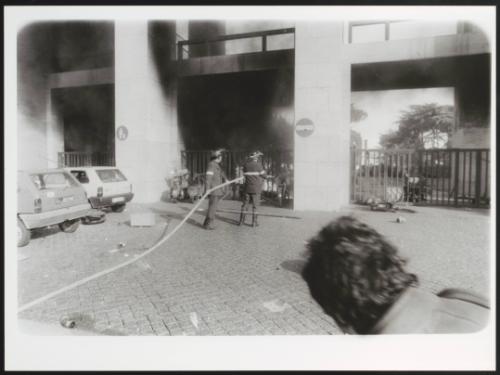 Two fire fighters putting out a blaze at Rome University after a student protest