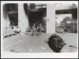 Two fire fighters putting out a blaze at Rome University after a student protest
