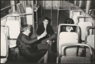 Two women and a young boy sit on the floor of a bus