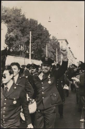 A procession of night watchmen march down the street 