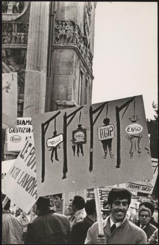 A man holds a hand painted gallows on a protest poster against the rising prices of oil 
