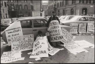 Two men with many hand written protest posters against the rising prices of petrol 