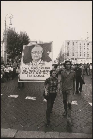 Protesters demonstrate in support of democracy in Chile, in the name of Allende, Chile's head of state who died under controversial circumstances in 1973.
The placard reads:
'con il popolo cileno nel nome di Allende contro il fascismo e la reazione ' = 'With the Chilean people, in the name of Allende, against Fascism and the reactionary regime'