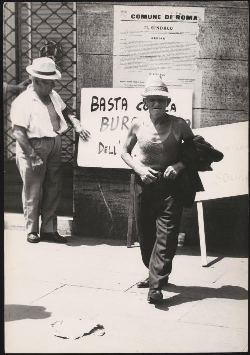 Two demonstrators in Rome, stand by a hand painted placard.