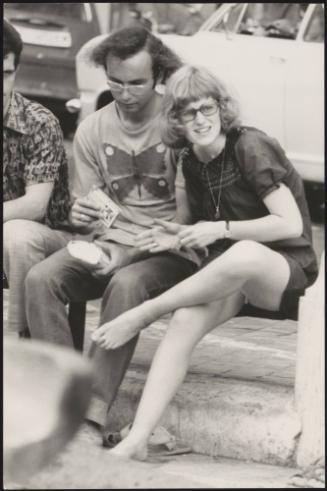 An Italian 'Pappagalli' man and a female tourist sitting down, Rome