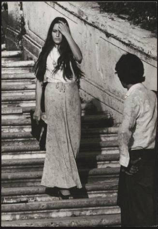 An Italian 'Pappagalli' man watches a female tourist walk down the Spanish Steps, Rome