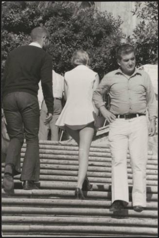 An Italian 'Pappagalli' man talks to a female tourist as they walk up the Spanish Steps, Rome
