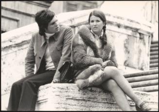 An Italian 'Pappagalli' man sits with a  female tourist by Trinità dei Monti, Rome