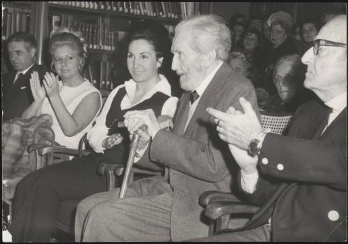 The poet Ezra Pound sitting in a room with applauding people