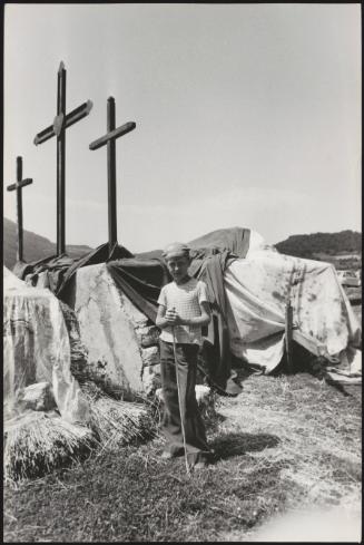 A young boy working on farmland in Pescolanciano, in the Molise region of southern Italy, photographed underneath three large crucifixes