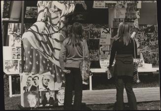 Two women with painted banners and photo-collages representing solidarity with Communism