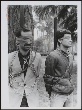 Two men are tied up and blindfolded in a satirical re-enactment of Iranian leader Khomeini executing opposition members 