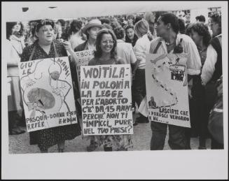 Three feminists wearing placards denouncing the law against abortion and criticising Pope Wojtyła about Poland's abortion law compared to Italy's