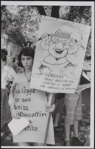 A young woman holds up home made placards criticising politician Amintore Fanfani