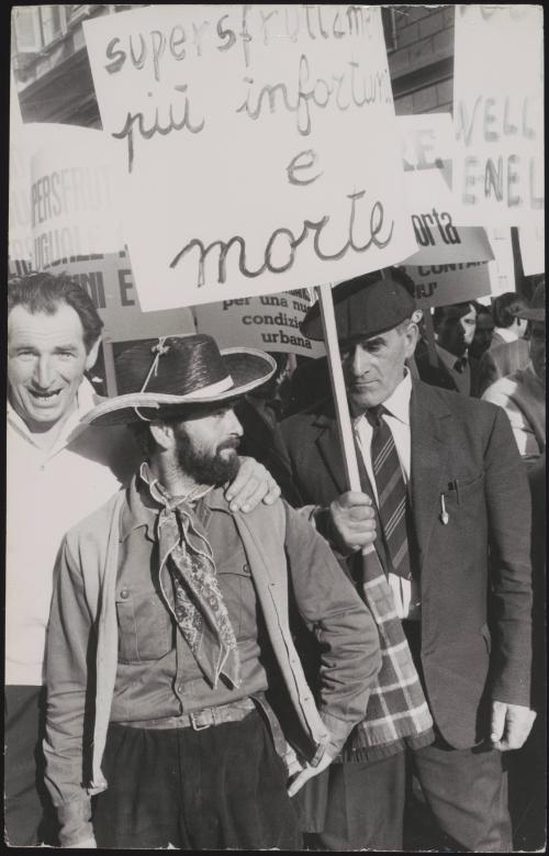 At a workers union strike in Milan, a man holds a placard reading 'Overworking leads to more accidents and death'