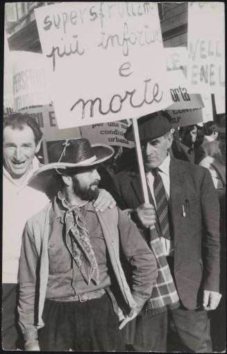 At a workers union strike in Milan, a man holds a placard reading 'Overworking leads to more accidents and death'