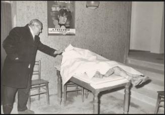 A man looks at a victim laid under a sheet in the aftermath of an earthquake, 1971
