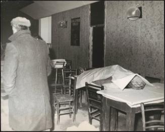 A man looks at a victim laid under a sheet in the aftermath of an earthquake, 1976