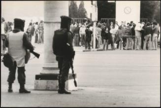 Riot police on stand by as protesters gather outside a building