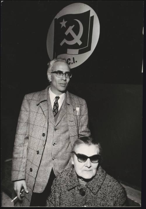 Rachele Torri, Pietro Valpreda's Great Aunt (seated). The Italian Communist Party flag hangs on the wall behind. 