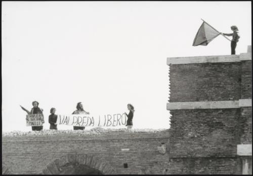 Five people protesting on the roof of a building against the unexplained death of Pino Pinelli and the incarceration of Peter Valpreda, accused of The Piazza Fontana bombings