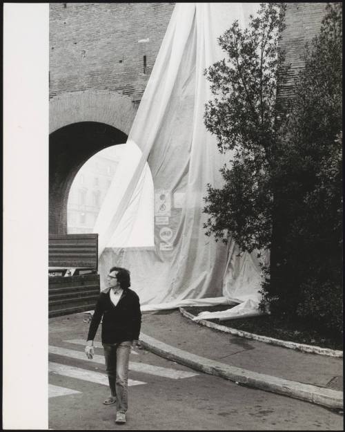 The erection of The Wall – Wrapped Roman Wall, Via Veneto and Villa Borghese, Rome, Italy, 1973-74. By artists Christo and Jeanne-Claude. The artist Christo walks by. 