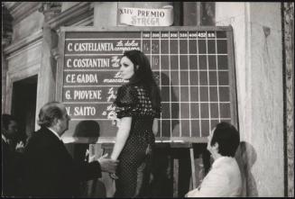 1970. Points are marked up on the chalk board for The Strega Prize by actress Rosanna Schiaffino, assisted by actor and prize founder, Guido Alberti. 
