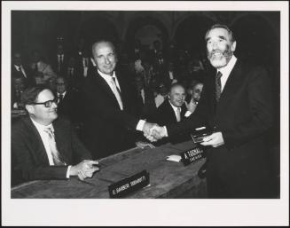The writer Mario Rigoni Stern shakes hands with Mr. Tognana while literary critic Giorgio Barberi Squarotti looks on